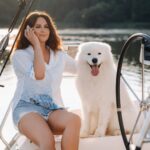 a happy woman with a big white dog on a white yacht in the sea