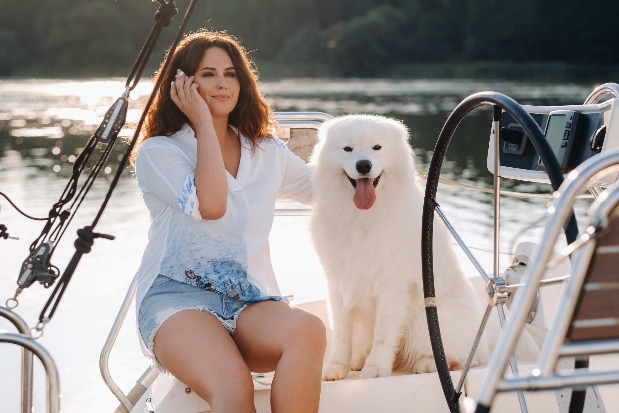 a happy woman with a big white dog on a white yacht in the sea
